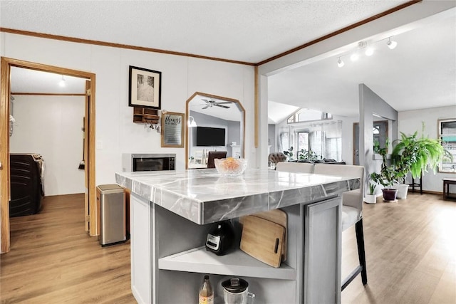 kitchen with a kitchen breakfast bar, a kitchen island, lofted ceiling, and light wood-type flooring