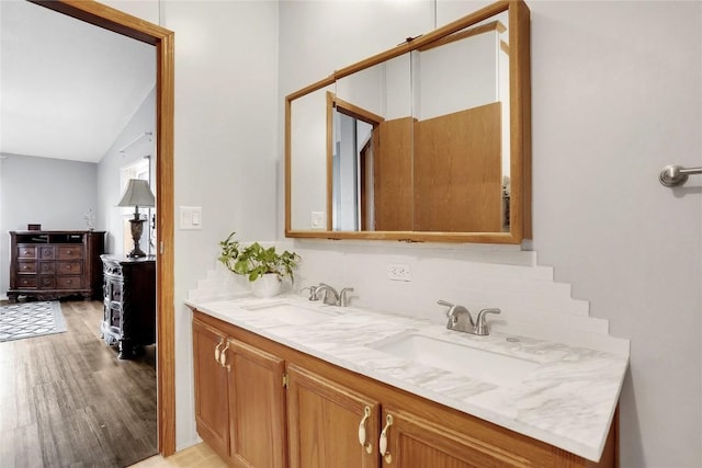 bathroom with wood-type flooring, vanity, and lofted ceiling