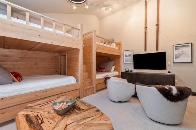 bedroom with high vaulted ceiling, carpet floors, and rail lighting