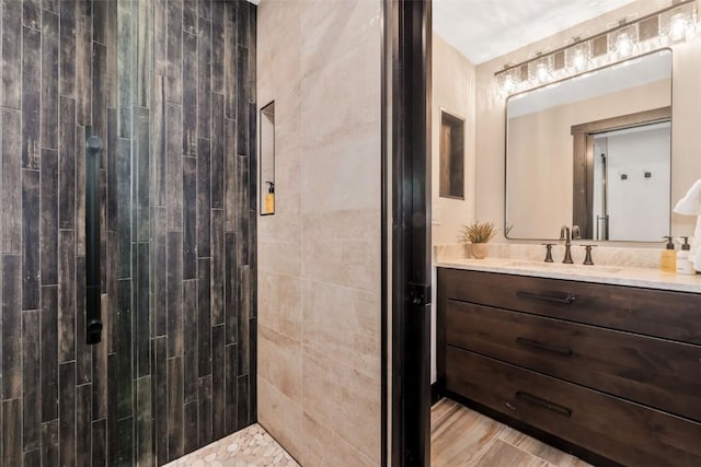 full bathroom with wood finished floors, a tile shower, and vanity