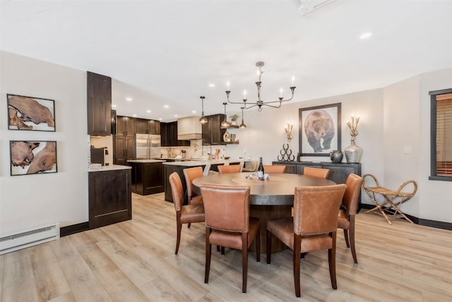 dining area featuring light wood-type flooring, a notable chandelier, baseboards, and a baseboard radiator