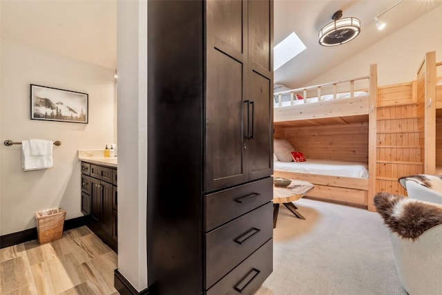 bathroom with lofted ceiling with skylight and baseboards