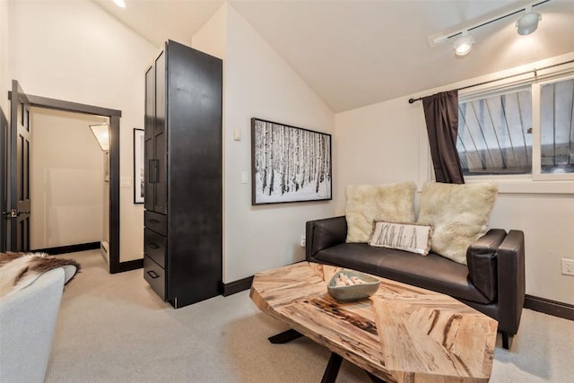 interior space featuring lofted ceiling, baseboards, rail lighting, and light colored carpet