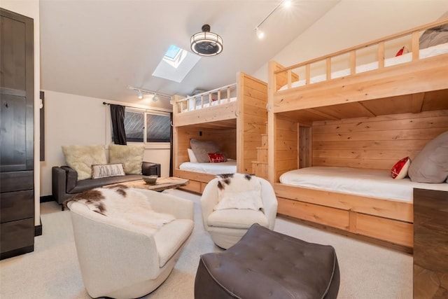 bedroom featuring vaulted ceiling with skylight, light colored carpet, and rail lighting