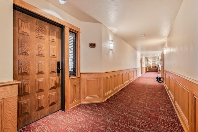 hall with wainscoting and dark carpet