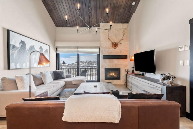 living area with a chandelier, a high ceiling, a fireplace, and wood ceiling