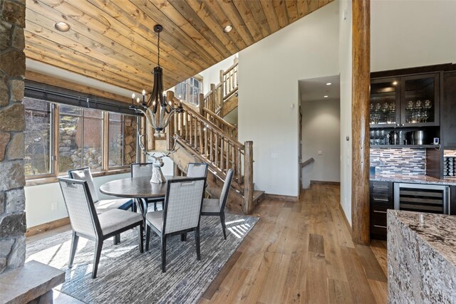 dining room with wooden ceiling, bar area, an inviting chandelier, wine cooler, and light hardwood / wood-style flooring