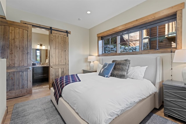 bedroom with a barn door and light hardwood / wood-style floors