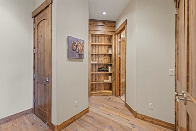 corridor with built in features and light hardwood / wood-style flooring