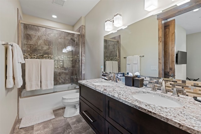 full bathroom with decorative backsplash, vanity, toilet, and bath / shower combo with glass door