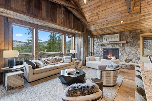 living room with high vaulted ceiling, a stone fireplace, light wood-type flooring, and wood ceiling