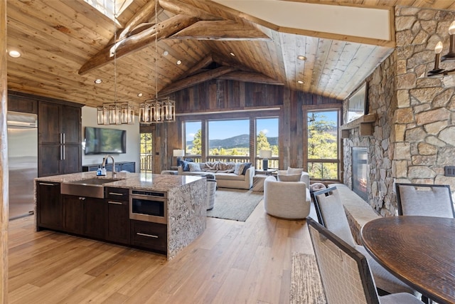 kitchen with wooden ceiling, light stone counters, high vaulted ceiling, built in appliances, and a fireplace