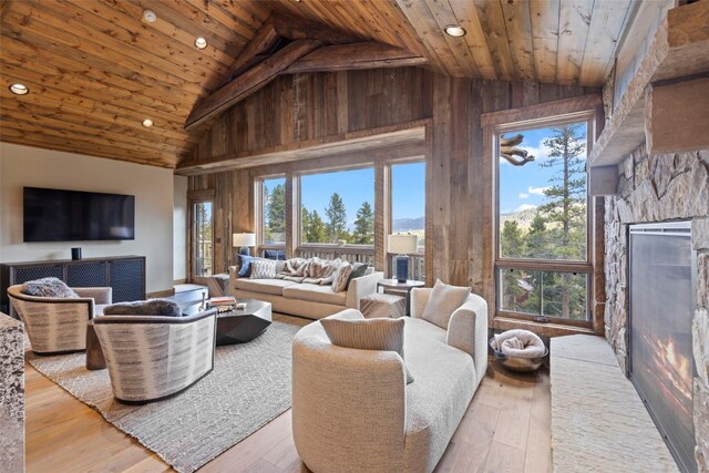 living room featuring light wood-type flooring, high vaulted ceiling, wood ceiling, and wood walls