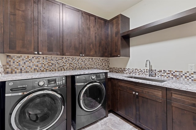 laundry area featuring washing machine and clothes dryer, cabinets, and sink