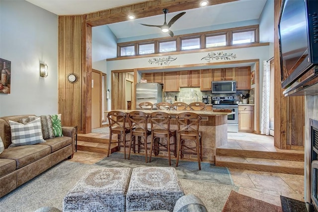 living room featuring ceiling fan, sink, and a towering ceiling