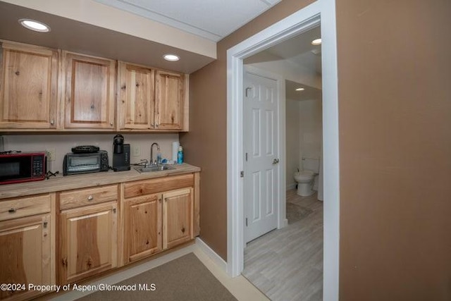 kitchen with sink, light brown cabinetry, and light hardwood / wood-style flooring