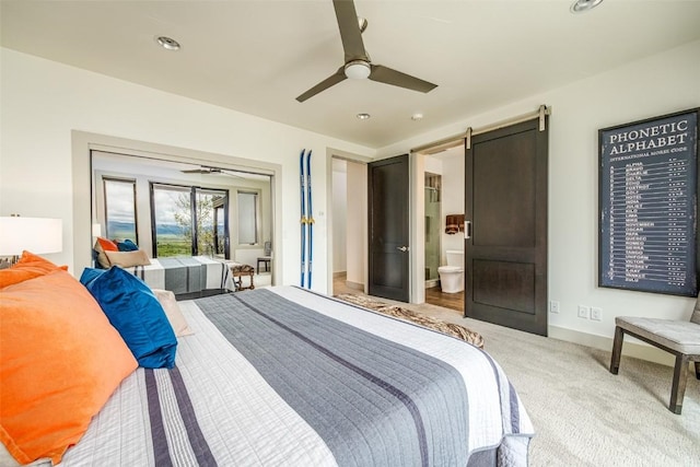 bedroom featuring ceiling fan, a barn door, carpet floors, and ensuite bath