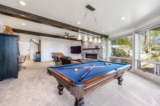 rec room with billiards, ceiling fan, a fireplace, beamed ceiling, and light colored carpet