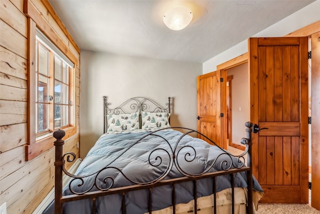 carpeted bedroom featuring wood walls