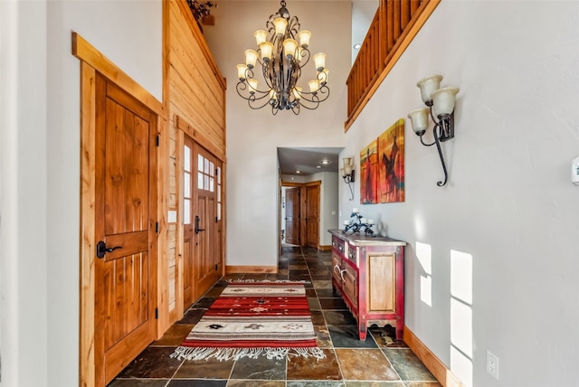 entrance foyer with an inviting chandelier, a towering ceiling, and stone finish floor