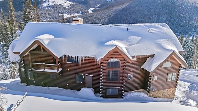 log-style house featuring a mountain view, log exterior, a forest view, and a balcony