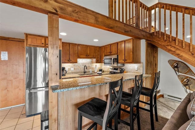 kitchen with stone counters, appliances with stainless steel finishes, a baseboard radiator, sink, and light tile patterned floors