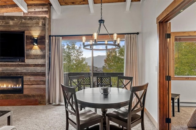 dining area featuring carpet, a healthy amount of sunlight, a notable chandelier, and beam ceiling