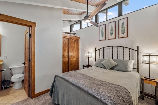 bedroom featuring connected bathroom, lofted ceiling with beams, light tile patterned floors, wooden ceiling, and ceiling fan