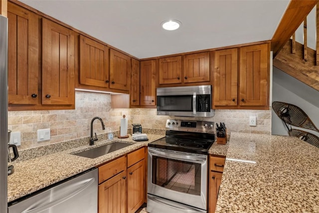 kitchen with stainless steel appliances, light stone countertops, sink, and decorative backsplash