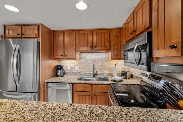 kitchen featuring stainless steel appliances, light stone countertops, and sink