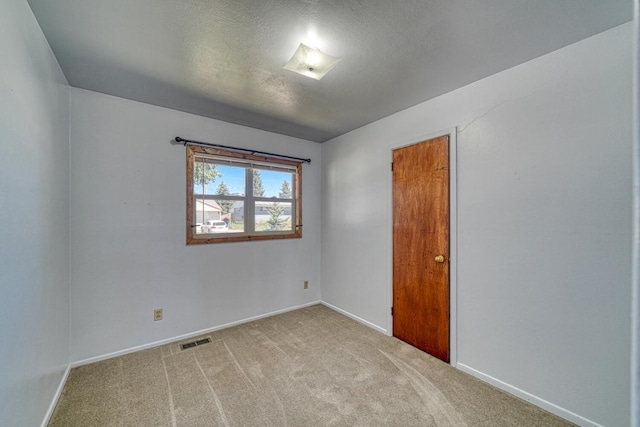 spare room featuring a textured ceiling and light colored carpet