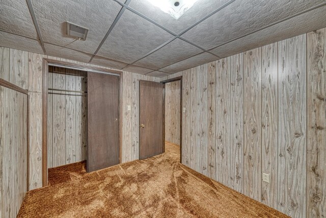 basement with carpet and wood walls