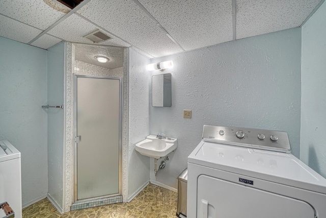 bathroom featuring a drop ceiling, walk in shower, and washer / clothes dryer