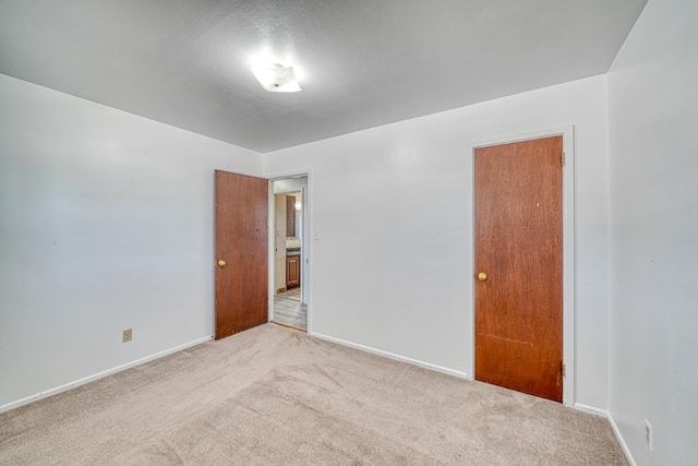 unfurnished room with a textured ceiling and light carpet