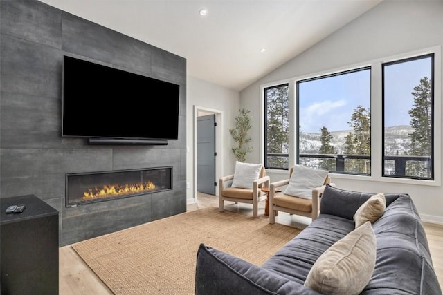 living room with lofted ceiling, a fireplace, light wood-style flooring, and recessed lighting