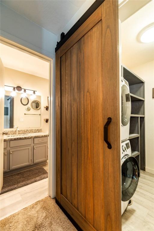 interior space featuring wood-type flooring, vanity, and stacked washer and clothes dryer