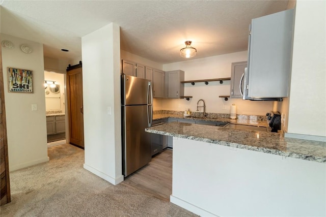 kitchen with kitchen peninsula, light carpet, stainless steel appliances, and sink