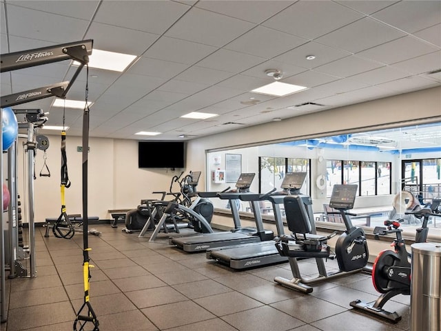 exercise room featuring a paneled ceiling and a wealth of natural light