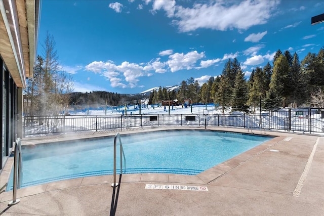 snow covered pool featuring a mountain view and a patio area