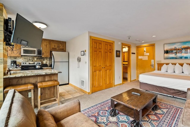 bedroom with white fridge and light colored carpet