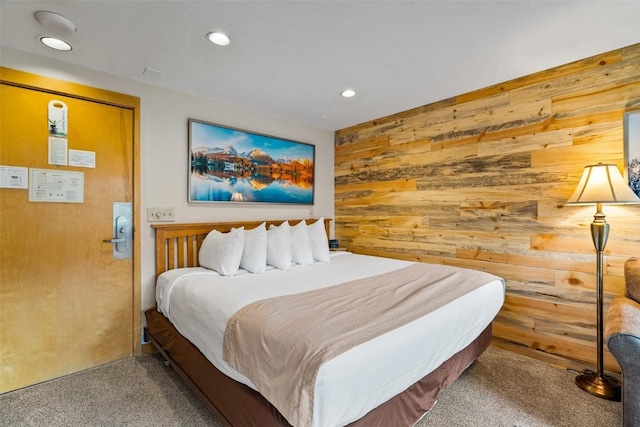 carpeted bedroom featuring wood walls