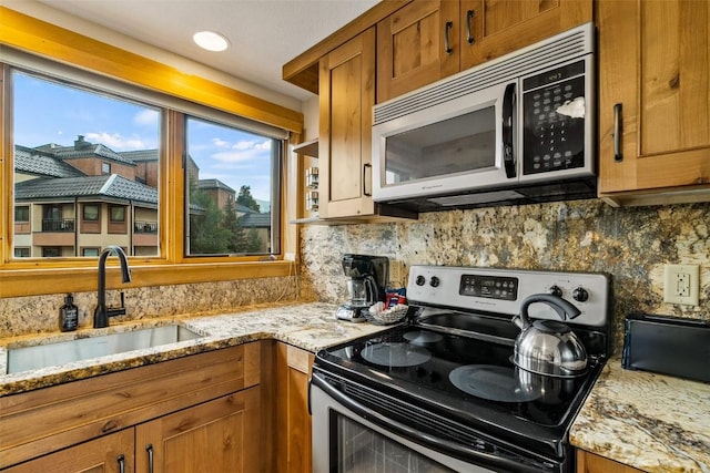 kitchen featuring light stone counters, stainless steel electric range oven, tasteful backsplash, and sink