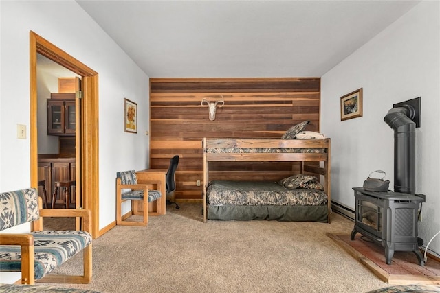 bedroom featuring carpet floors, a wood stove, and wooden walls