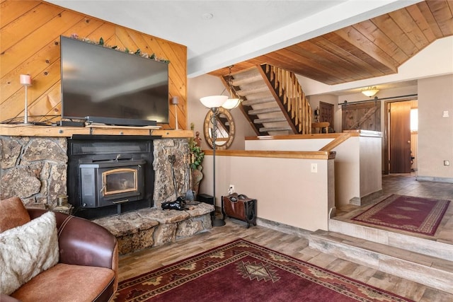 living room with hardwood / wood-style floors, beam ceiling, and a wood stove