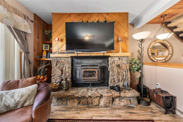 living room with beam ceiling, a wood stove, and wood walls