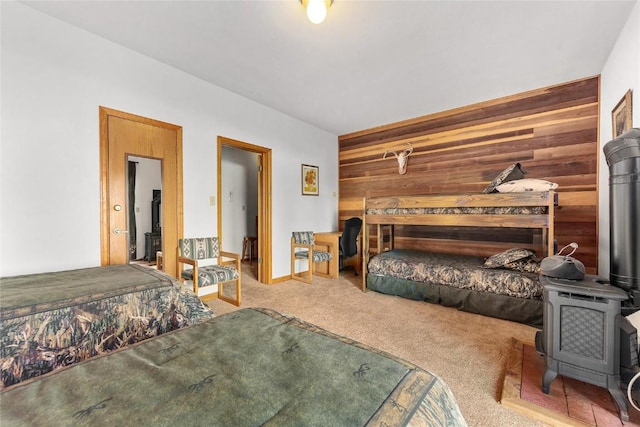 carpeted bedroom with a wood stove and wood walls