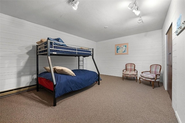 carpeted bedroom featuring a textured ceiling, rail lighting, and baseboard heating