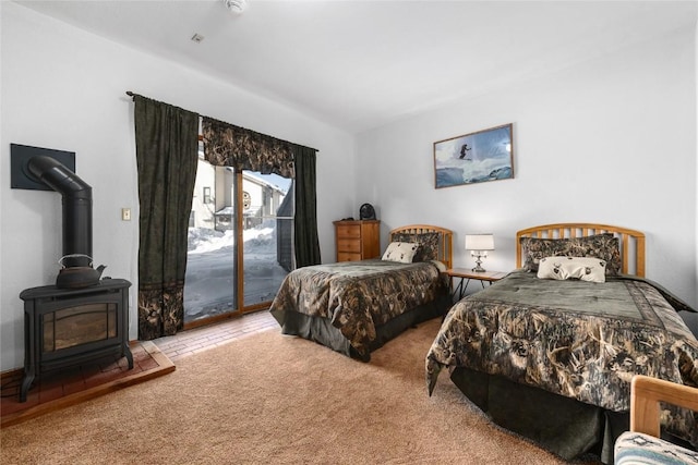 carpeted bedroom featuring access to outside and a wood stove