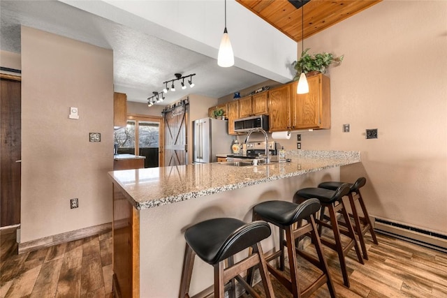 kitchen featuring kitchen peninsula, pendant lighting, stainless steel appliances, and light hardwood / wood-style flooring