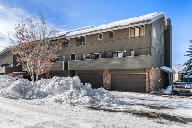 snow covered rear of property featuring a garage